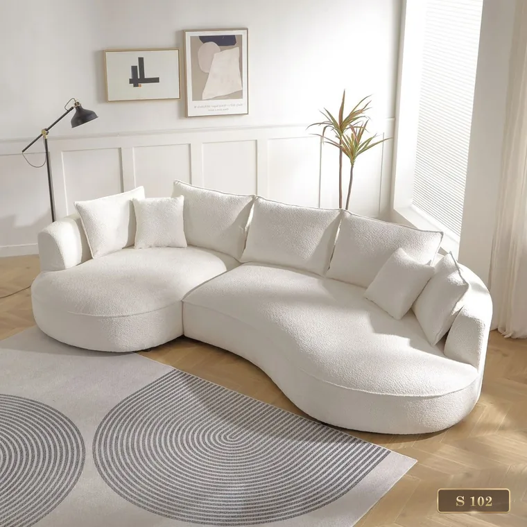 Curved sectional sofa with an integrated chaise in a bright room, catalogue reference S 102
