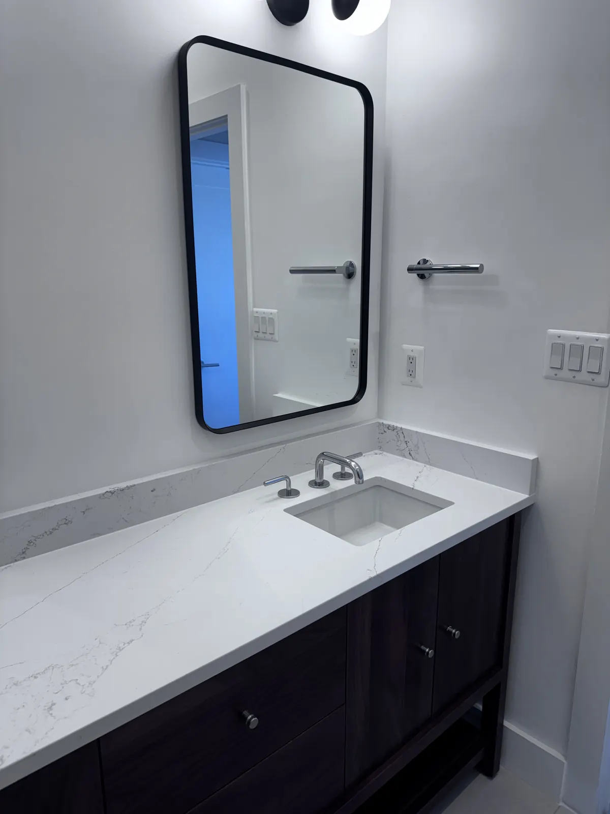 Quartz vanity top with black framed mirror and brushed fixtures