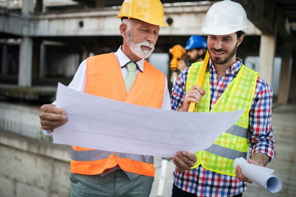Construction workers reviewing architectural plans for an office renovation project led by general contractors in Washington DC.