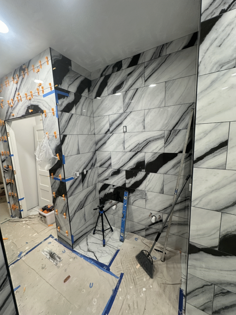 In-progress bathroom remodel in Arlington, VA showing marble wall tile installation with tools and materials on-site.