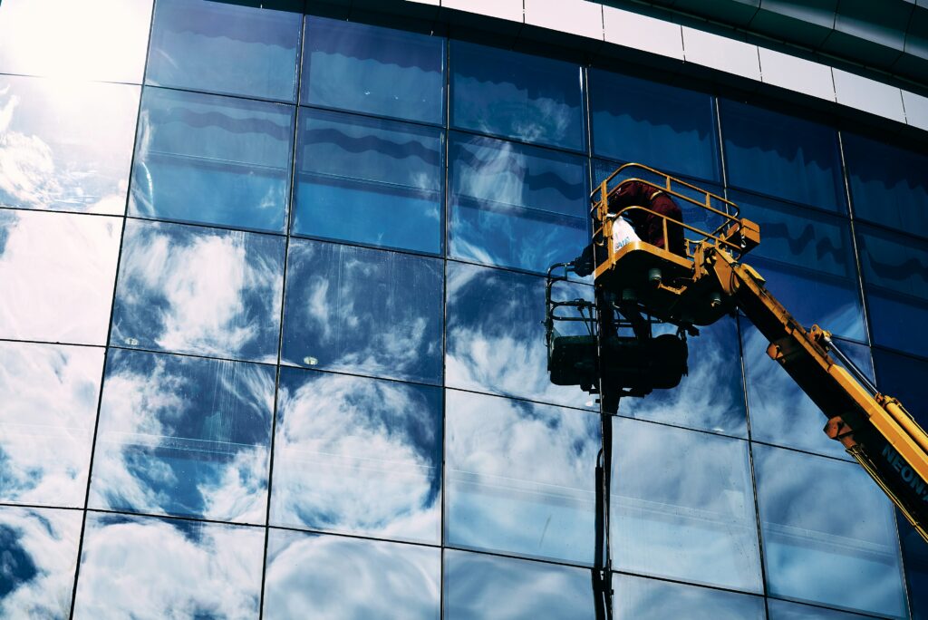 Construction worker performing glass window maintenance on a commercial building, handled by general contractors in Washington DC.