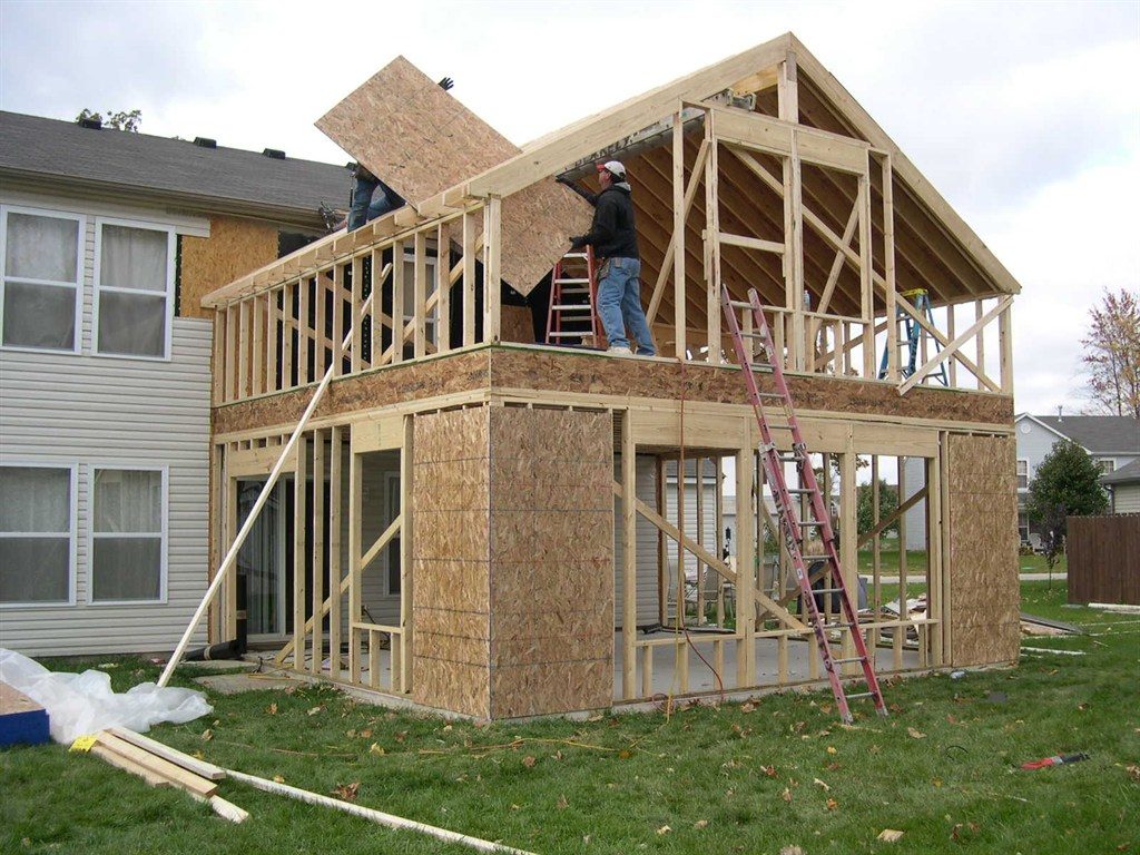 Two-story house under construction with workers and materials