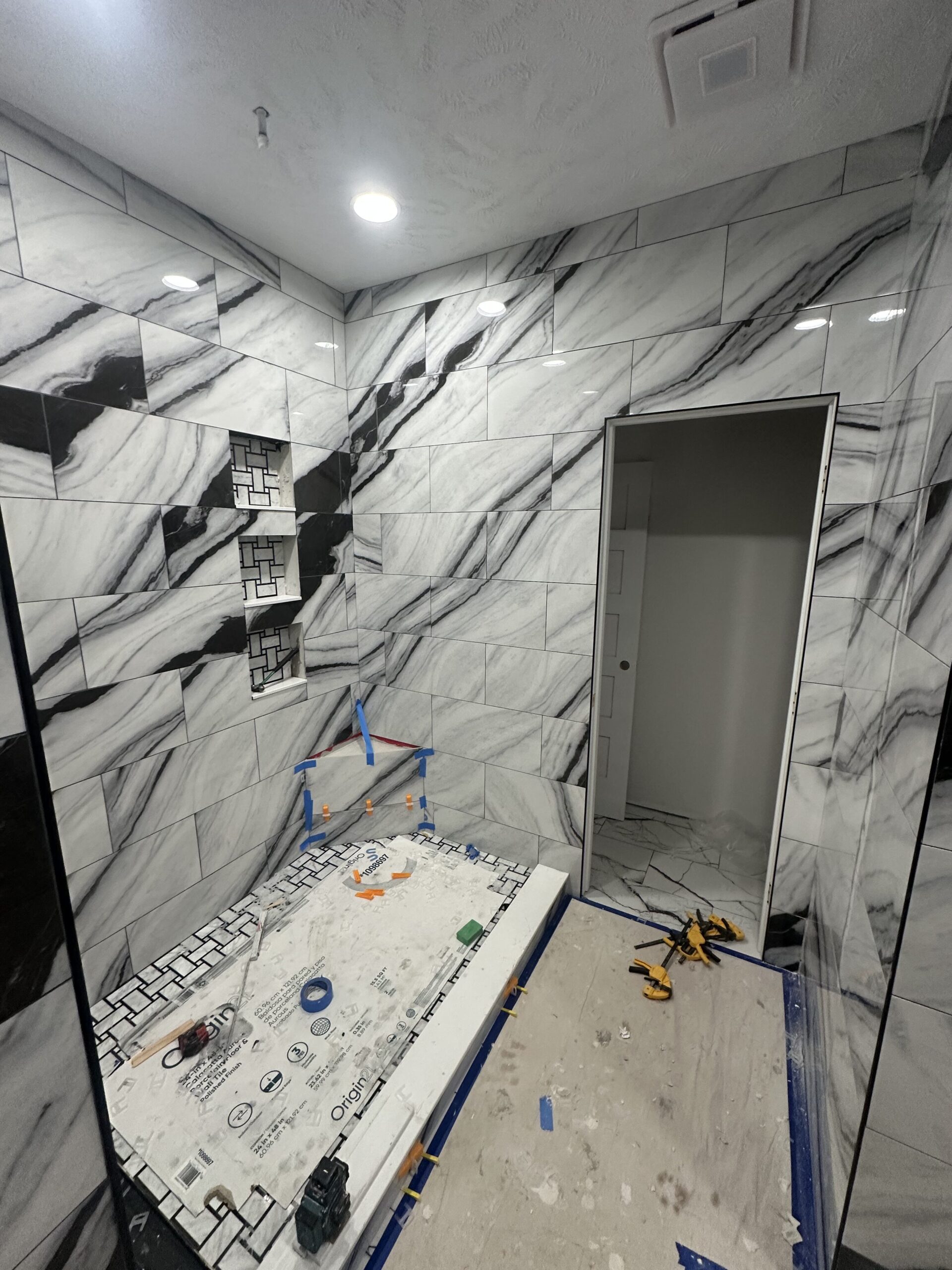 Bathroom under construction with marble tiles and tools scattered