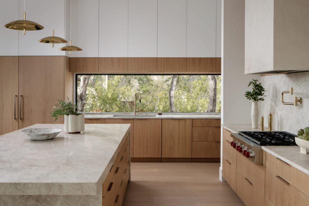 A sleek, airy kitchen with light wood cabinetry and marble countertops